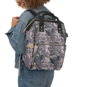 Smiling person in a denim jacket and jeans carries the Camo Diaper Backpack With Hunting Concealment Camouflage Sitka Optifade Open Country over one shoulder.